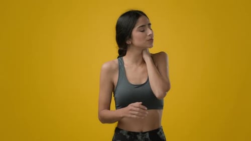 Young Woman Stretches Neck Against Yellow Background