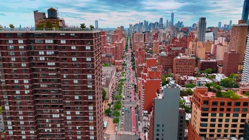 Multiple cars move by the multi-lane road along the long straight street. Urban scenery of New York
