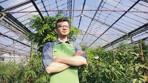 Smiling Adult in Greenhouse Surrounded by Plants