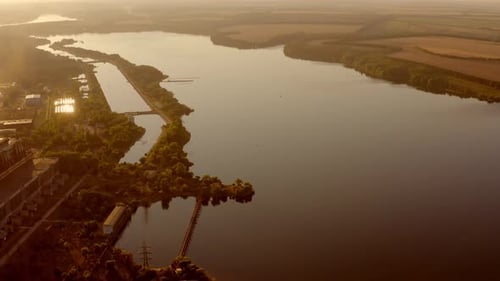 Evening rural scenery. Panoramic view of wide river near the fields at sunset.
