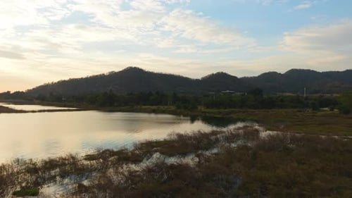 Calm Natural Landscape with Wetlands Shallow Water Mountains Distant Trees Cloudy Sky and a Red