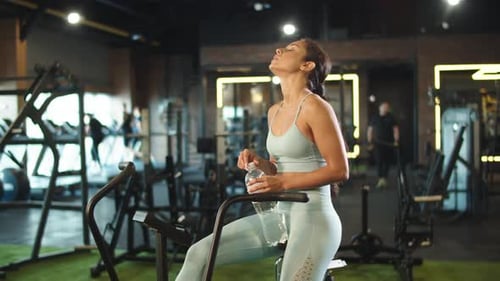 Closeup Tired Fit Girl Holding Water In Sport Club. Exhausted Sport Woman Wiping Sweat At Gym. At...