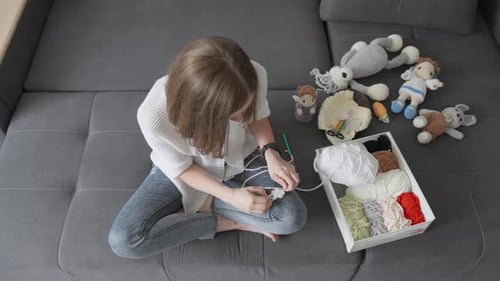 Woman Crocheting Colorful Toys on Sofa