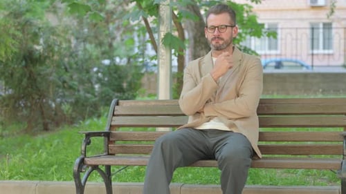 Bearded Man Sitting and Thinking on Park Bench