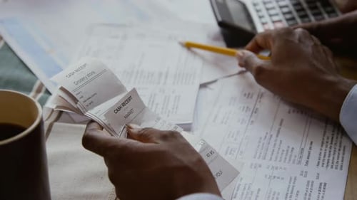 Hands Holding Receipts and Pointing at Documents Managing Finances