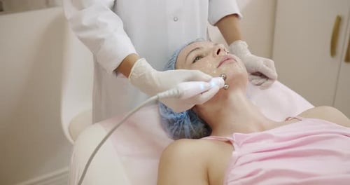 Kosmetikerin gibt Gesichtsmassage mit Massagegerät, Schwerpunkt Hautpflege, Gesichtsmassage