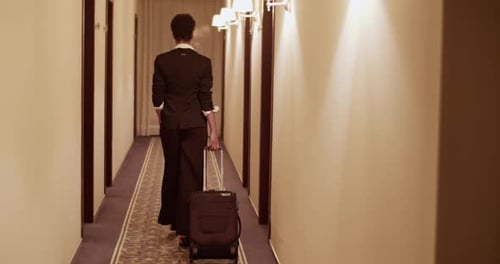 Anonymous Classy Woman with Suitcase Walking in Hotel Hallway