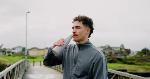 Runner, fitness and man drinking water on bridge for running break, hydration and minerals