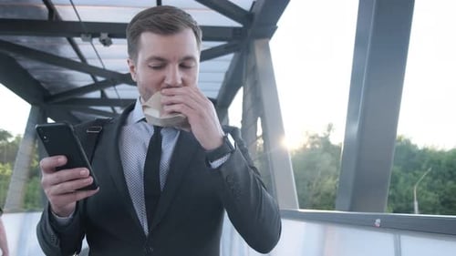 Man in Suit Eats Burger While Using Phone