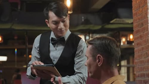Waiter with Tablet Taking Order from Man in Restaurant