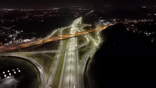 Illuminated Highway Interchange at Night Aerial View of Modern Road Infrastructure with Light Trails