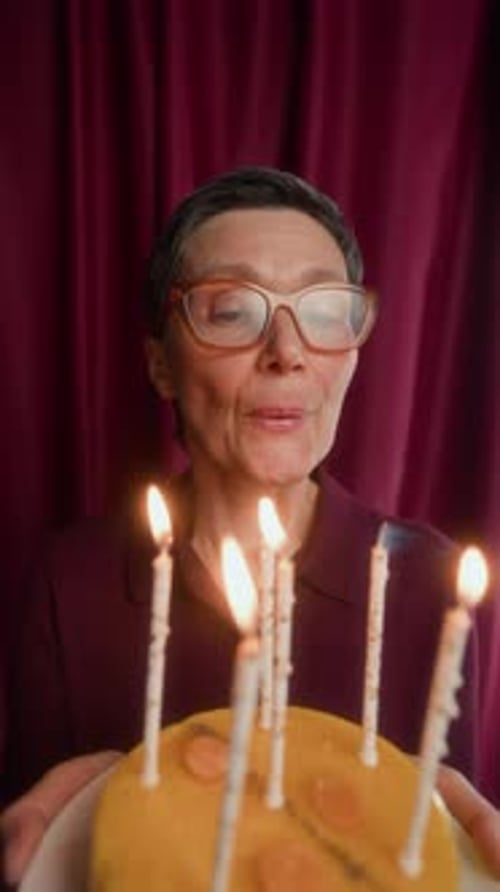 Woman with cake blowing out birthday candles