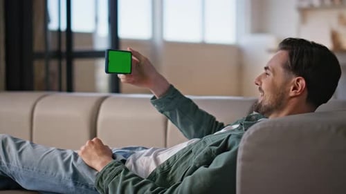 Man Relaxing on Couch with Phone Green Screen