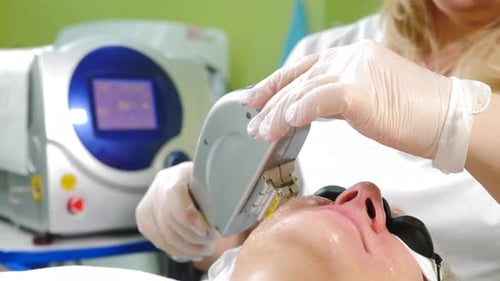 Woman Receiving Laser Facial Treatment in Clinic
