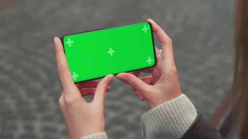 Young Woman Hands Hold Smart Phone with Horizontal Green Screen Outdoors Internet Mobile Smartphone