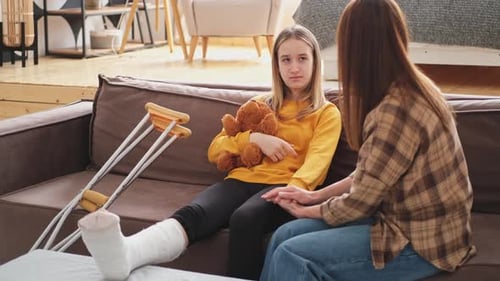 Concerned Woman with Teen with Broken Leg on Couch