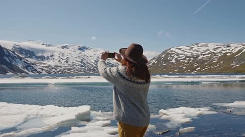 Woman Tourist on the River Bank in a Mountainous Area and Takes Photo on Smartphone