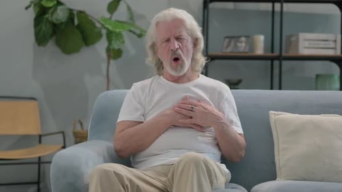 Old Man with Chest Pain Sitting on Sofa at Home