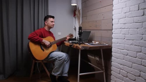 Man Plays Acoustic Guitar in Home Studio Setting