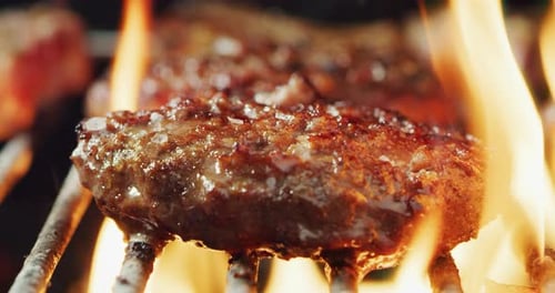 Nahaufnahme von Fleisch auf dem Grill eines Barbecues, das auf hoher Flamme zubereitet wird. Konzept: Freunde, Urlaub, Freizeit