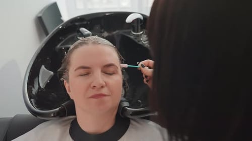 Woman having eyebrows brushed after hair dye