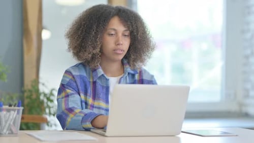 Young Woman Works on Laptop at Table Indoors