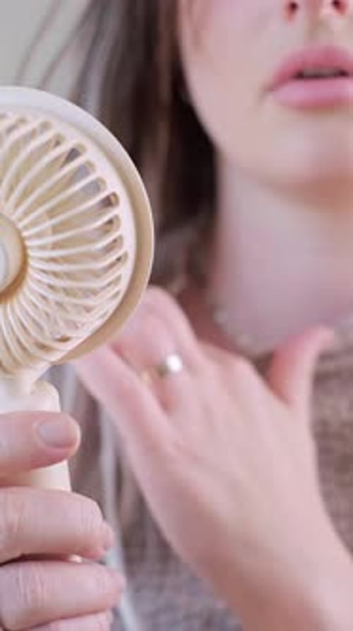 Woman Uses Personal Fan to Cool Herself