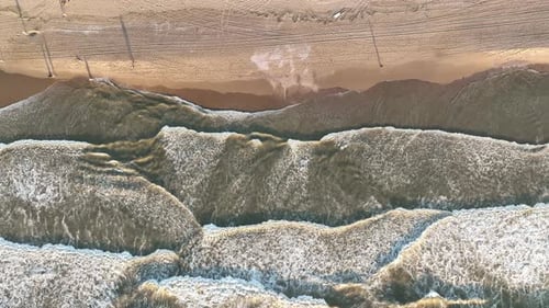 An aerial view of the wide beach and waves. Seascape from a drone during sunset.