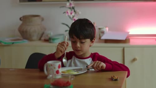 Boy Eats Breakfast at Table Indoors