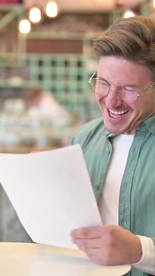 Middle Aged Man Celebrating Success on Documents in Cafe, vertical video