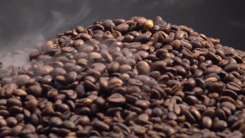 Pile of steaming roasted coffee beans close up