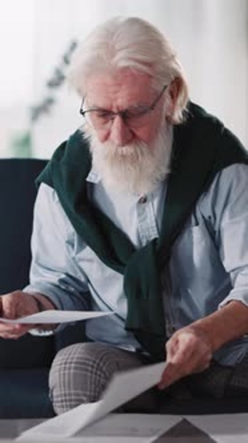 Senior Handsome Old Man Reading Document Office Papers Freelancing From Work Sititng at Home Wearing