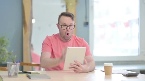 Man Celebrates with Tablet at Desk
