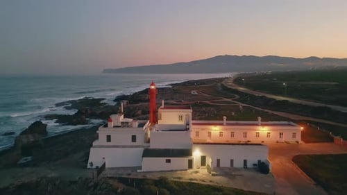 Aerial View of Lighthouse on Rocky Coast at Sunset