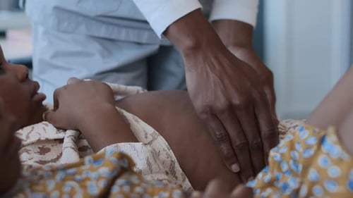 Les mains d'un médecin méconnaissable palpant l'abdomen d'une fillette d'âge préscolaire