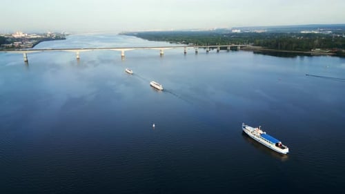 Cargo Ship and Passenger Ferry Navigating River Under Bridge Clip