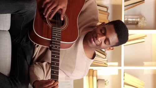 Young Adult Playing Acoustic Guitar at Home