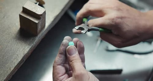 Juwelier, der gerade dabei ist, einen blauen Quarz-Schmuckring in einer Schmuckwerkstatt von Hand herzustellen
