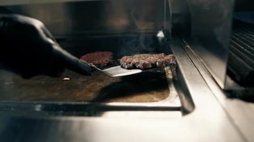 kitchen close-up chef flips delicious juicy patties on grill with spatula for smash burger