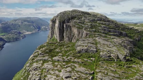 Lush Vegetation And Towering Rocky Mountains Surrounding A Peaceful Fjord