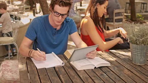 Young Adults Studying Together at an Outdoor Cafe