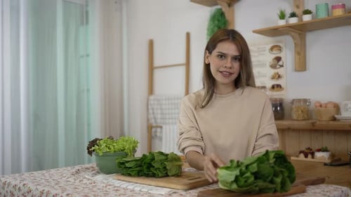 Smiling Woman Holding Lettuce in Kitchen