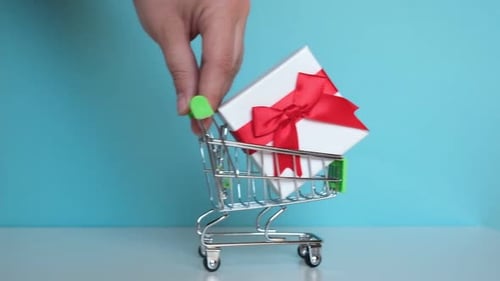 Hand Pushing Miniature Supermarket Trolley with Present