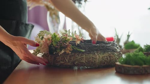 Woman Arranging Decorative Flower Wreath on Table