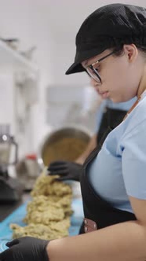 Professional Baker Spreading Dough on Table in Bakery
