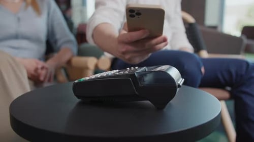Closeup of a Man Hands Paying the Bill Via a Smartphone Using NFC Technology in Restaurant Sitting