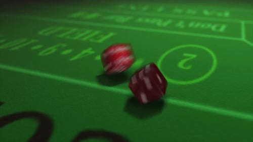 Pair of dice thrown onto a craps or crapaud table with glittering poker machines in a casino backgro