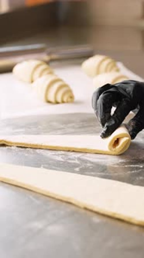 Gloved Hand Forming Crescent Roll from Dough