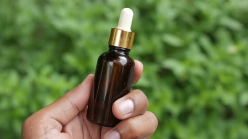 Hand Holding Cosmetic Bottle with Dropper