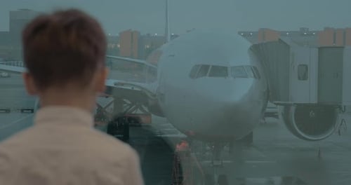 Kid Waiting at Airport and Looking at Plane Through the Window